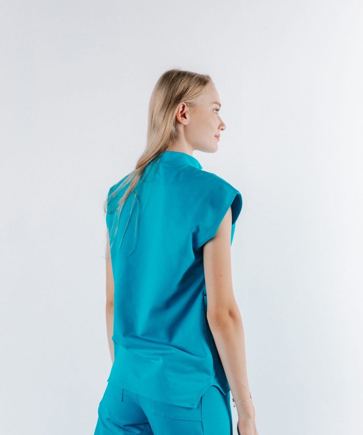 scrub medical albastru azure uniforma doctori costum spital studenti medicina12 scaled Vedere din spate a unei doamne doctor ce poarta o bluza tunica de scrub medical albastru azure.Uniforma medicala albastru azure este din bumbac 95% si elastan 5% cu croiala fit.