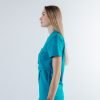 Vedere laterala a unei doamne doctor ce poarta o bluza edgy de scrub medical albastru azure.Uniforma medicala albastru azure este din bumbac 95% si elastan 5% cu croiala fit.