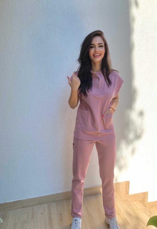 Fotografie cu vedere din profil a unei cliente in timp ce poarta o bluza tunica un scrub medical roz pudra ce reprezinta uniforma medicala reprezentativa a unui doctor