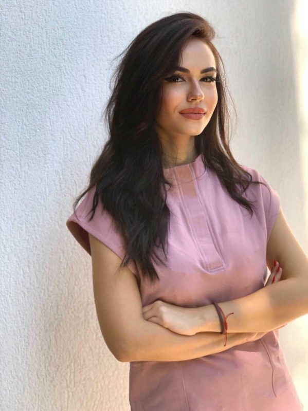 Fotografie cu vedere din profil a unei cliente in timp ce poarta o bluza tunica un scrub medical roz pudra ce reprezinta uniforma medicala reprezentativa a unui doctor