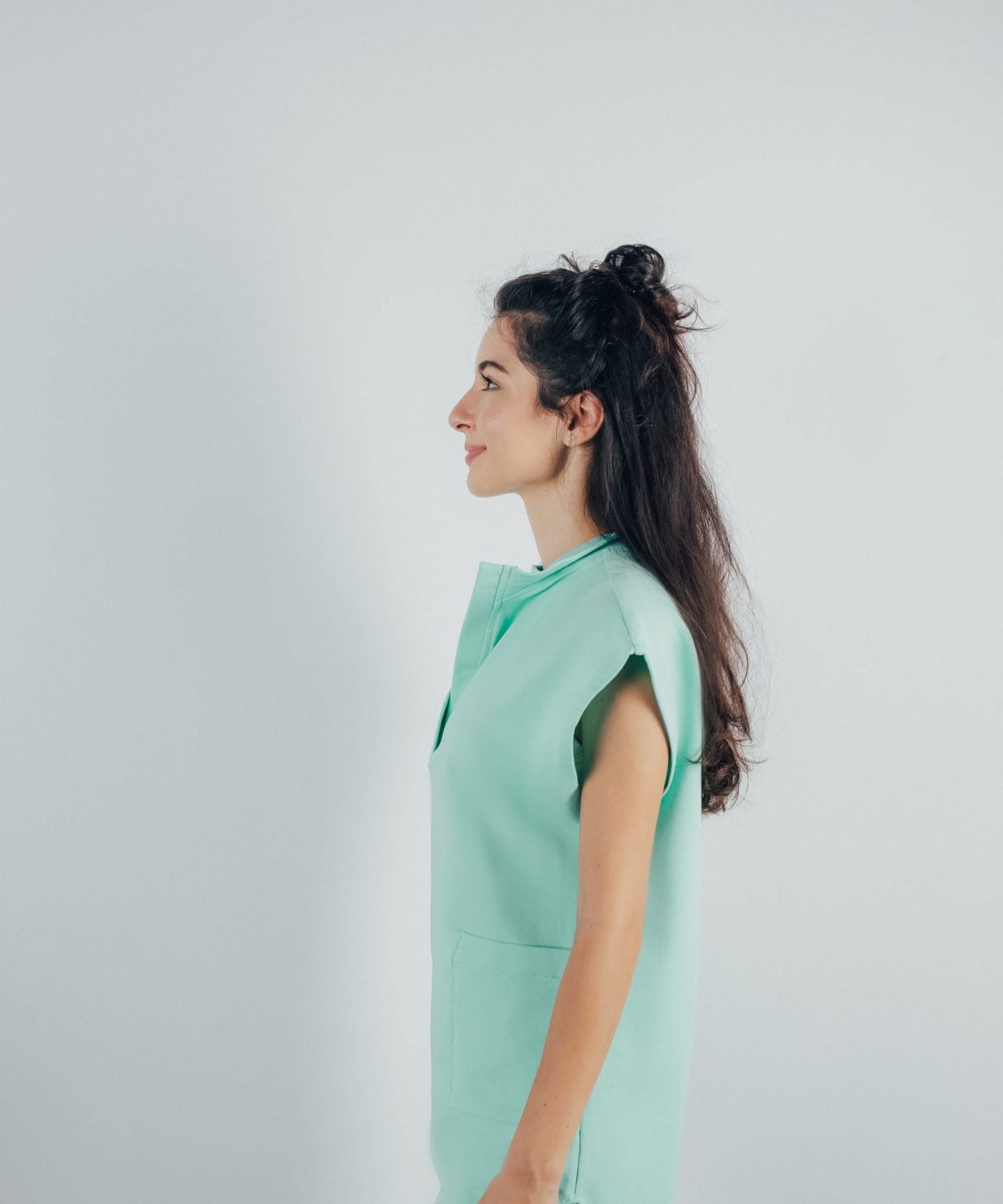 Fotografie cu vedere din lateral a unei studente la medicina in timp ce poarta o bluza tunica de scrub medical verde menta ce reprezinta uniforma medicala reprezentativa a unui doctor