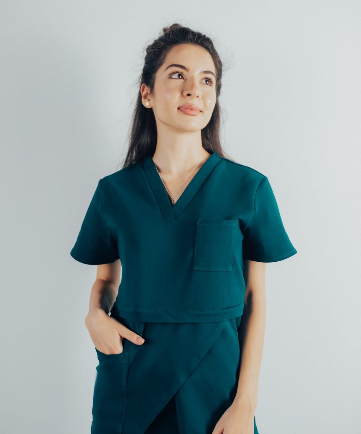 Fotografie cu vedere din fata a unei studente la medicina in timp ce poarta o bluza edgy de scrub medical turcoaz inchis ce reprezinta uniforma medicala reprezentativa a unui doctor