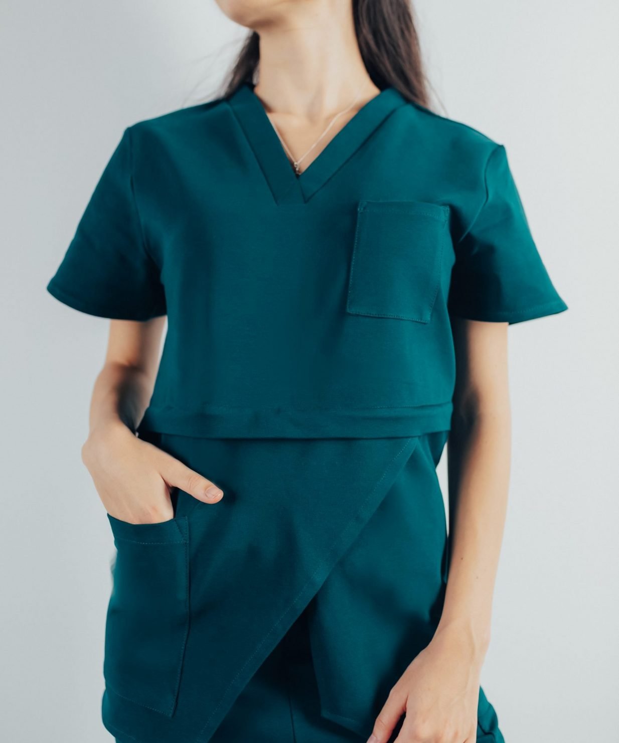Fotografie cu vedere din fata a unei studente la medicina in timp ce poarta o bluza edgy de scrub medical turcoaz inchis ce reprezinta uniforma medicala reprezentativa a unui doctor