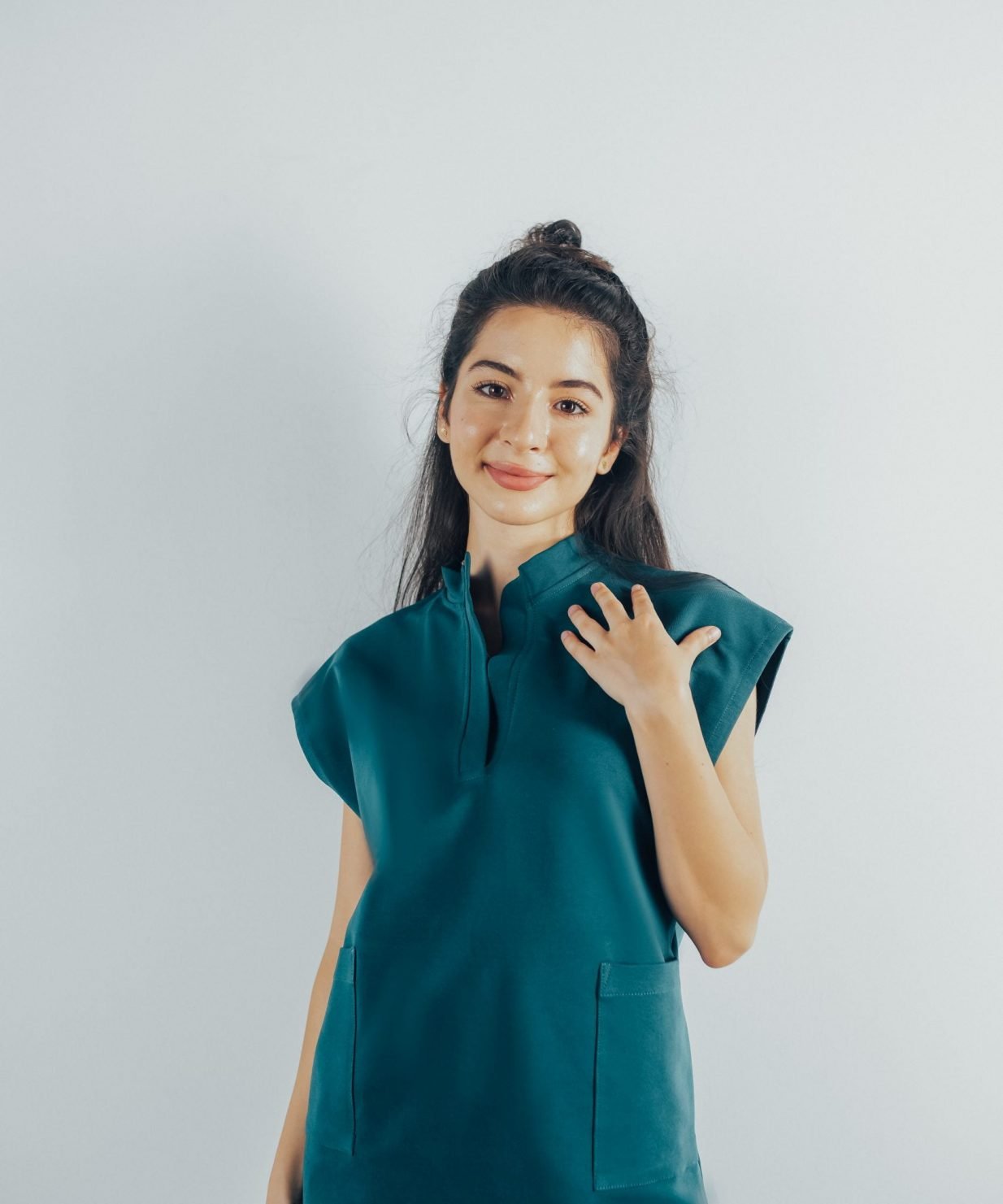 Fotografie cu vedere din fata a unei studente la medicina in timp ce poarta o bluza tunica de scrub medical turcoaz inchis ce reprezinta uniforma medicala reprezentativa a unui doctor